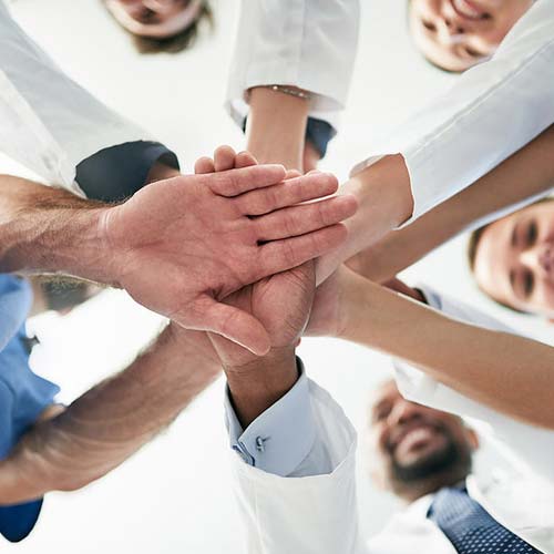 GPs and Integrative Medicine doctors putting hands together to show teamwork.